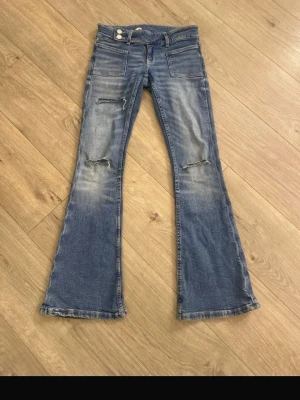 Blå utsvängda jeans - Säljer ett par blå jeans med utsvängda . Perfekta för en trendig och avslappnad stil.  Pyttelite slitage nere vid foten. Hör av er vid frågor😊💞storlekslappen har åkt på ena sidan men den syr jag såklart på innan leverans. Inget som syns