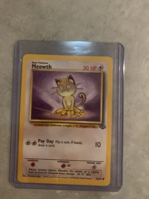 Pokémonkort Meowth Base Set - Säljer ett klassiskt Meowth Pokémonkort från Base Set-serien. Kortet har gul ram, motiv av Meowth som sitter på mynt och texten 'Pay Day'. Kortet är inplastat i ett skyddsfodral. Perfekt för samlare eller Pokémonfans!