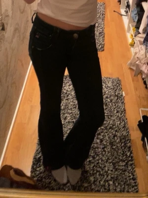 Mörkblå bootcut jeans - Snygga mörkblå bootcut jeans med klassisk femficksdesign och låg midja. Jeansen har en tidlös look och passar perfekt till en avslappnad stil. Materialet är troligtvis bomull med lite stretch för extra komfort. Sytt ut dom längst ner, vilket ger en cool extra look! 