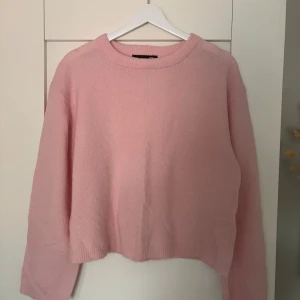 Ljusrosa stickad tröja - Söt ljusrosa stickad tröja med rund hals och långa ärmar. Tröjan har en avslappnad passform och ribbade muddar vid halsen. Perfekt för lager på lager och enkel att matcha med jeans eller kjol. Aldrig använd!