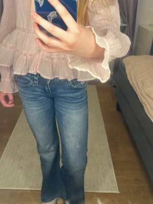 Blå bootcut jeans med slitningar - Säljer ett par blå jeans med fina detaljer på fickorn. Funkar bra både i vardagen och i finare sammanhang. Säljer då jag har växt ur jeansen.🌸