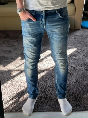 Blå dondup jeans  med slitningar - Säljer ett par blå dondup jeans med snygga slitningar och tvättade detaljer. Jeansen har klassisk femficksmodell, normal midja och smal passform hela vägen ner. Modellen är 176cm och väger 62kg. Storlek 31, slim fit. Hör av er om ni har några frågor!☺️