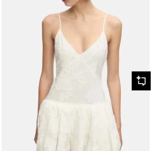 Studentklänning! - Söt vit kortklänning med tunna axelband och v-ringning. Klänningen har spetsdetaljer över hela tyget och en lätt volang i kjolen. Öppen rygg med knytband upptill ger en romantisk känsla. Perfekt för student! Prislapp kvar!❤️