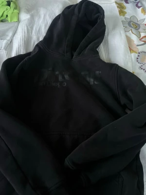 Svart DirtCult hoodie med tryck - Svart hoodie från DirtCult med stort tryck på bröstet där det står 'DirtCult San Diego'. Klassisk känguruficka framtill och huva. Tillverkad i mjukt bomullsmaterial som är skönt att ha på sig. Perfekt för en avslappnad streetwear-look. Passar xs