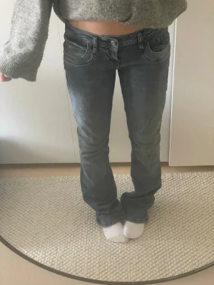 Blå bootcut jeans med kontrastsömmar - Säljer ett par blå bootcut jeans med snygga kontrastsömmar och låg midja. Jeansen har klassiska fem fickor och en lätt tvättad look. Perfekta för dig som gillar en avslappnad men ändå trendig stil.