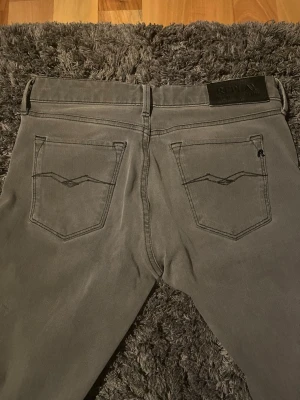 Gråa Replay jeans med raka ben - Snygga gråa jeans från Replay med raka ben och klassisk femficksmodell. Jeansen har detaljerade bakfickor med broderad linje och Replay-logga på fickan fram. Tillverkade i mjukt denimtyg som sitter skönt och passar till många olika stilar.