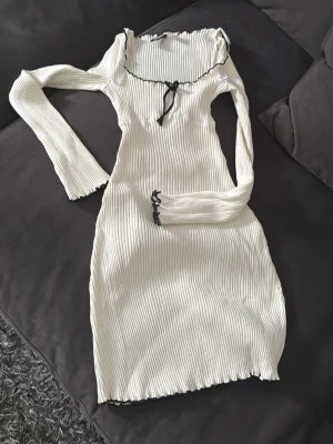Vit ribbad klänning från H&M - Supersöt vit ribbad klänning från H&M med lång ärm och svart kontrastkant vid halsen. 