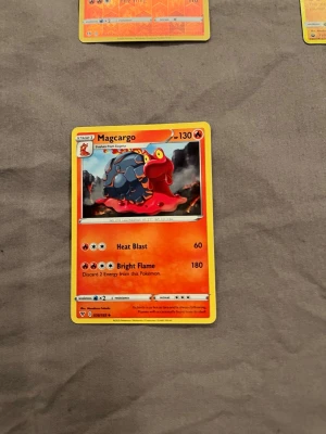 Magcargo Pokémonkort - Magcargo Pokémonkort med röd och orange ram, motiv av Magcargo i mitten. Kortet är tillverkat av papper och har detaljerad grafik samt text om attackerna Heat Blast och Bright Flame. Perfekt för samlare eller Pokémon-fans.