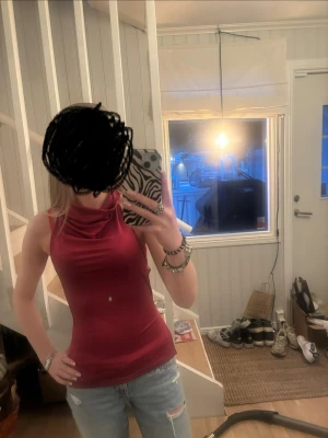 Mörkröd ärmlös linnetopp - Snygg mörkröd ärmlös linnetopp med öppen rygg och hög hals. Toppen har en tight passform och är tillverkad i ett mjukt, stretchigt material som sitter skönt mot kroppen men även med justerbara band i ryggen. Perfekt att styla med jeans eller kjol för en trendig look.