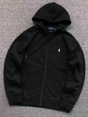 Svart hoodie från Polo Ralph Lauren - Snygg svart hoodie från Polo Ralph Lauren med dragkedja framtill och klassisk huva med dragsko. Ikoniska vita loggan broderad på bröstet. Hoodien har känguruficka och ribbade muddar vid ärmar och nederkant. Perfekt för en avslappnad och stilren look.
