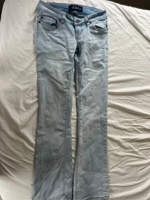 Ljusblå bootcut jeans från G rise - Säljer ett par ljusblå bootcut jeans från g rise med klassisk femficksdesign och snygga kontrastsömmar. Jeansen är tillverkade i mjukt denimtyg som ger en avslappnad look. Perfekta för dig som gillar en retro vibe.