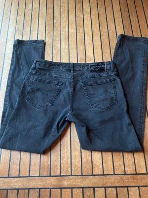 Svarta jeans från Jacob Cohen - Snygga svarta jeans från Jacob Cohen med klassisk femficksmodell och raka ben. Jeansen har en diskret logotyp på bakfickan och patch i läder bak i midjan. Materialet är mjukt och stretchigt för extra komfort.