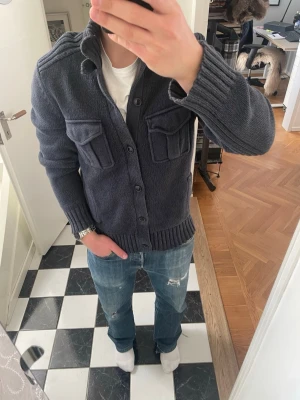 Grå cardigan  - Tja säljer en snygg grå cardigan som passar perfekt för våren och sommaren. Tröjan är i storlek L men passar även M. Modellen på bilderna är 175 och 72kg 