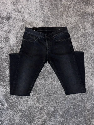 Svarta slim fit jeans från Dondup - Snygga svarta slim fit jeans från Dondup med klassisk femficksdesign och diskret tvättad look. Jeansen har normal midja och slim-fit passform, perfekta till en avslappnad stil. Tillverkade i mjukt denimtyg för skön känsla hela dagen.
