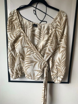 Wrap topp - Gina Tricot - ”Beata” wrap topp från Gina Tricot. Beigea färgen är mer lik mina egna bilder, inte lika ljus som modellbilderna. Storlek 36, men passar även en 34. I mycket fint skick 🌸