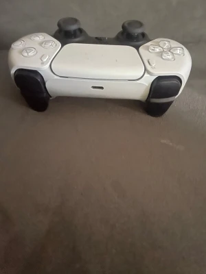 Vit och svart PS5 DualSense handkontroll - Säljer en snygg PlayStation 5 DualSense handkontroll i vit och svart design. Kontrollen har ergonomisk form, två analoga spakar, touchpad och klassiska PlayStation-knappar. Perfekt för gaming på PS5 och har USB-C-port för laddning.