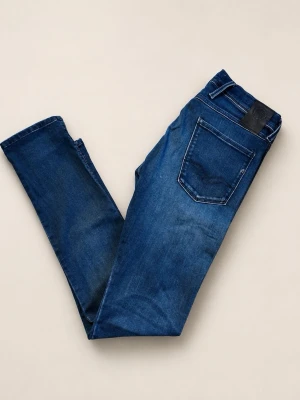 Blå Replay Anbass jeans - Snygga blå slim fit jeans från Replay med klassisk femficksdesign och läderpatch bak i midjan. Jeansen har en något tvättad look och smal passform som sitter tajt längs benen. Perfekta för en trendig och avslappnad stil. Modellen är 181 och väger ungefär 80kg. Finns en liten (knappt en 1cm) slitning av mindre betydelse intill sömnen under gylfen.
