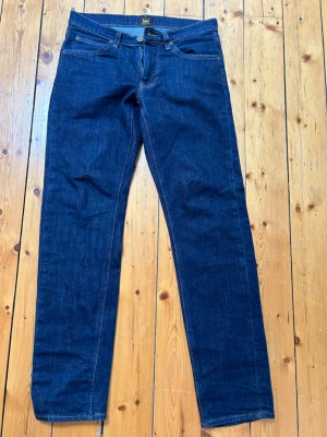 Mörkblå raka jeans från Lee - Snygga mörkblå jeans från Lee med klassisk rak passform och fem fickor. Jeansen har kontrastsömmar och är tillverkade i slitstark denim. Perfekta för en clean och tidlös look. Storlek W29 L32, använda 2 ggr. 