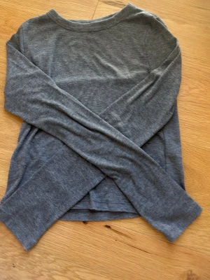 Grå ribbad långärmad topp Gina Tricot - Säljer en enkel och stilren grå ribbad långärmad topp från Gina Tricot. Toppen har rund halsringning och är tillverkad i mjukt material som passar perfekt till alla dina outfits.