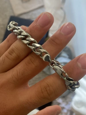 Tungt silverfärgat kedjearmband - Snyggt och robust armband i silverfärgad metall med breda, platta länkar i en klassisk kedjedesign. Perfekt för dig som gillar en stilren och tidlös accessoar som sticker ut lite extra. Låset är rejält och håller armbandet säkert på plats.