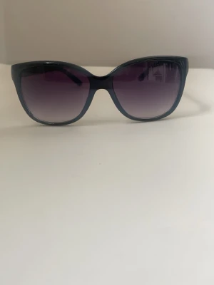 Svarta cat eye solglasögon - Snygga svarta solglasögon med cat eye-form och mörka, tonade glas. Bågarna är i plast och har en klassisk look som passar till många stilar. Perfekta för soliga dagar och ger en cool vibe.