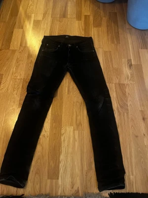 Svarta slim fit jeans W27 L32 Luke - Säljer ett par svarta slim fit jeans med klassisk femficksdesign och raka ben. Jeansen har svarta sömmar och knappgylf. Passar perfekt till en avslappnad och stilren look.