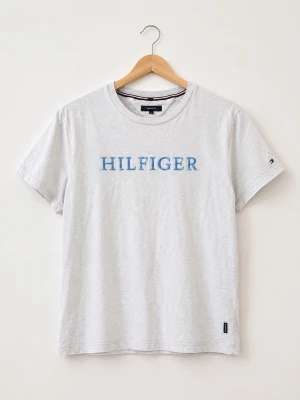 Grå Hilfiger t-shirt i bomull - Snygg ljusgrå t-shirt från Tommy Hilfiger med blått HILFIGER-tryck på bröstet och liten logga på ärmen. Klassisk rund hals och normal passform. Tillverkad i mjuk bomull som känns skön mot huden. Perfekt till jeans eller shorts.