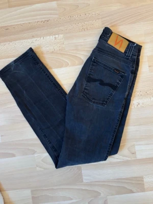 Nudie Jeans W27 – mörkgrå/svart tvätt - Snygga jeans från Nudie Jeans i mörkgrå/svart tvätt med lätt slitna detaljer för en snygg vintagekänsla. Klassisk 5-ficksmodell med Nudies karakteristiska söm på bakfickorna. Bekväm passform och stretchig denim som sitter fint. 📏 Storlek: W27 🎨 Färg: Mörkgrå/svart ✅ Bra skick, se bilder för detaljer 👖 Perfekta till både vardag och festligare tillfällen Skickas snabbt eller hämtas enligt överenskommelse. #nudiejeans #jeans #w27 #denim #svartajeans #vintage #s