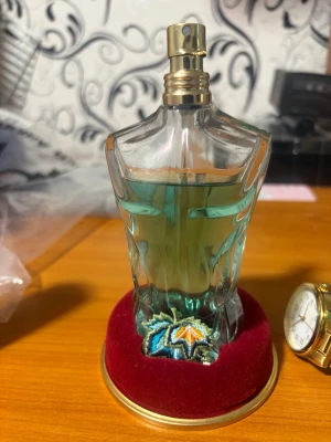 Jean Paul Gaultier Le Beau Paradis - Jean Paul Gaultier Le Beau Paradis Garden EdP i en unik flaska formad som en manlig torso. Parfymen har en blågrön färg och flaskan står på en röd sammetsbas med broderad blomdetalj. En lyxig och iögonfallande doft för dig som gillar exklusiva parfymer.