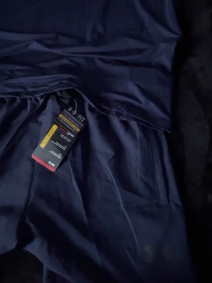 Mörkblå leggings från Under Armour - Snygga mörkblå set från Under Armour. Tillverkade i ett stretchigt funktionsmaterial som andas och sitter skönt på kroppen. Perfekta för träning eller chill. Fickor på sidorna för mobilen.