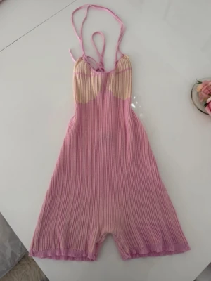 Rosa ribbad stickad playsuit - Säljer en söt ribbad stickad playsuit i rosa och ljusbeige toner. Har snörning i ryggen❣️