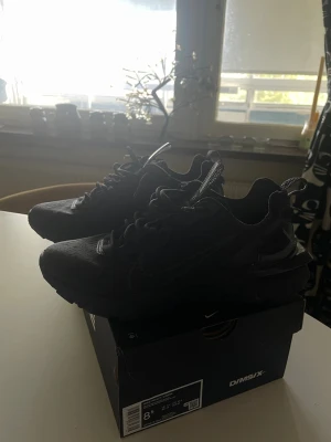 Svarta Nike D/MS/X sneakers - Snygga helsvarta Nike D/MS/X sneakers med låg profil och sportig design. Skorna har en chunky sula, meshdetaljer och klassisk snörning. Perfekta för dig som gillar streetwear och vill ha en stilren look.