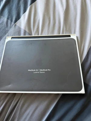 Apple MacBook läderfodral svart - Snyggt svart läderfodral från Apple för MacBook Air och MacBook Pro. Fodralet är tillverkat i äkta läder och har en stilren, minimalistisk design med diskret Apple-logga. Såldes flera år sedan för cirka 2000kr nypris i apple butiken