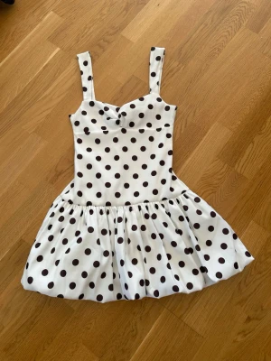  Ny slutsåld Vit kort prickig klänning från Zara  - Supersöt vit klänning med svarta prickar och breda axelband. Klänningen har en figurnära överdel och utställd kjol som ger en lekfull look. Perfekt för dig som gillar retrostil och vill sticka ut lite extra.