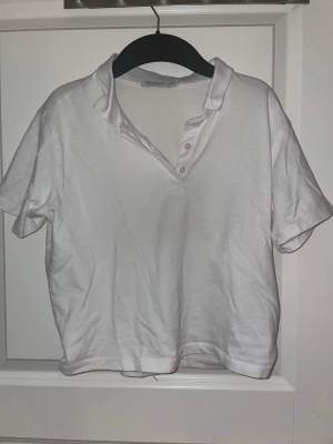 En kort vit tröja från stradivarius i storlek XS med en krage och knappar. Knappt använt.