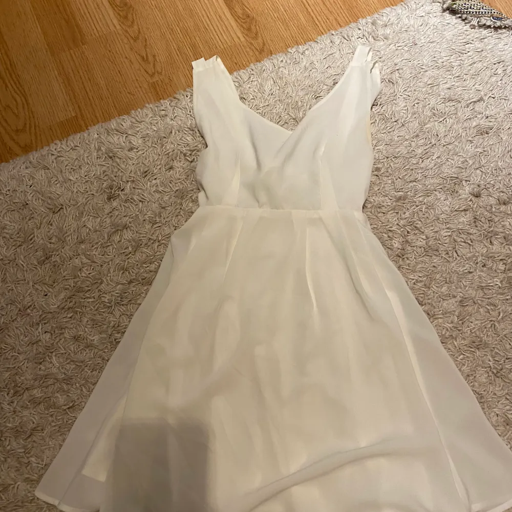 En fin vit klänning som ha en roset i ryggen . Klänningar.