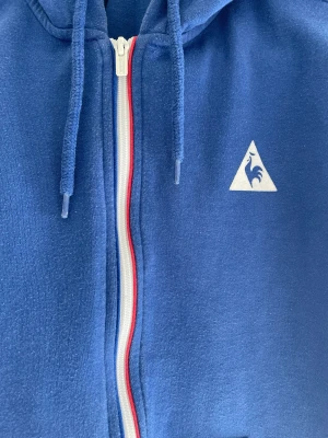 Tröja Le Coq Sportif - Storlek S/M blå tröja med luva franska flaggan vid zippen syns på bilden de en linje som e röd o en blå ska reppa france ☺️