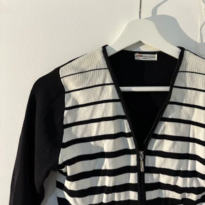 randig kofta - Svart-vit randig zip-up tröja med trekvartärmar. 