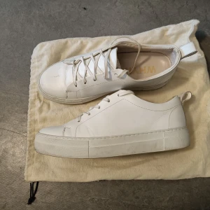 Vita skinnsneskers - Vita sneakers från Whyred. Storlek 43 men få de är lite stora passar de en med storlek 44 bäst. Mycket fint skick, förutom ett litet skrap på ovansidan av ena skon. Knappt använda.