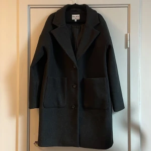 Mörkgrå kappa nakd - En mörkgrå kappa från nakd. Endast använd en gång då jag trodde att jag beställde en svart kappa. Storlek 40, Frakt tillkommer 