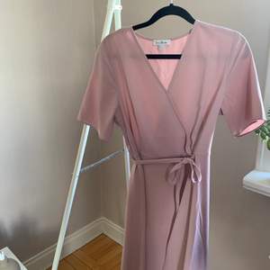 Supersöt rosa klänning från Love Bonito i storlek UK 12. Band att knyta runt midjan för att anpassa formen men är ingen wrap-dress i sin helhet. Sparsamt använd, skick utan anmärkningar. SKICKAS med postnords fraktpåse för 63kr, önskas spårbart tillkommer