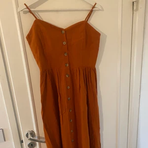 Klänning - Orange/brun långklänning med knappar hela vägen. Jättefin och skön sommarklänning. Lite längre än knähöjd