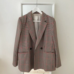 H&M kavaj - Snygg beige, mönstrad kavaj med inslag av rött och brunt. Fickor framtill, samt knappar så den går att stänga. Använd några gånger men ser i princip ut som ny!! 