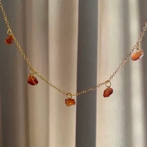 Halsband med karneol (finns i silver) - Kort halsband med äkta karneol. Finns även i silver. OBS! Kristallerna är äkta och ser därför olika ut i form och färg och ditt halsband kan se annorlunda ut än det på bilden