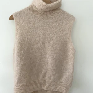 Stickad väst - Stickad väst med turtleneck, använd en gång. Lite mindre i passformen, ganska ljus lite varmare beige färg. Ordinarie pris ca 400 kr. 