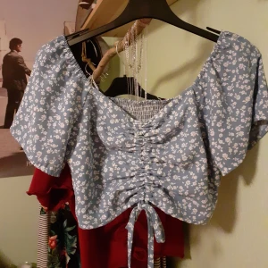 Sommartopp - Fin sommartopp från Sellpy. Blommig och med ett snöre framtill. Mycket bra skick