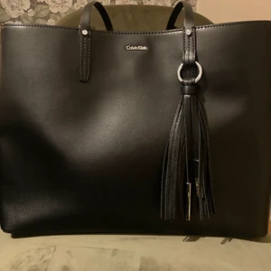 Calvin Klein väska - 🖤Större mycket rymlig väska från CK🖤 mycket fin väska från CK som aldrig är använd och säljes för mycket förmånligt pris. Köpt på CK i USA. Avtagbar detalj på framsidan