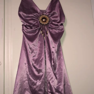 Lila boho klänning  - Denna klänning är till för dig som är kär i alternativt och lite annorlunda kläder. Klänningen har ett smycke vid bröstet gjort av pärlor och snäckor. Tyvärr vet jag ej vilken storlek men den passar mig med storlek 38 och funkar på mindre storlekar. 