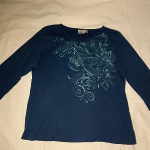Topp - Fin långärmad topp med snirkliga mäster och stenar. Är lite sliten och har små hål på framsidan.
