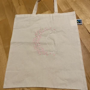 Totebag broderad - Broderad totebag med tryck av en måne vars baksida är klädd av en blommor. Sprillans ny totebag med brodering gjord av mig. Ifall du vill ha ett annat tryck, skicka iväg ett meddelande så fixar jag! Du står för frakten.
